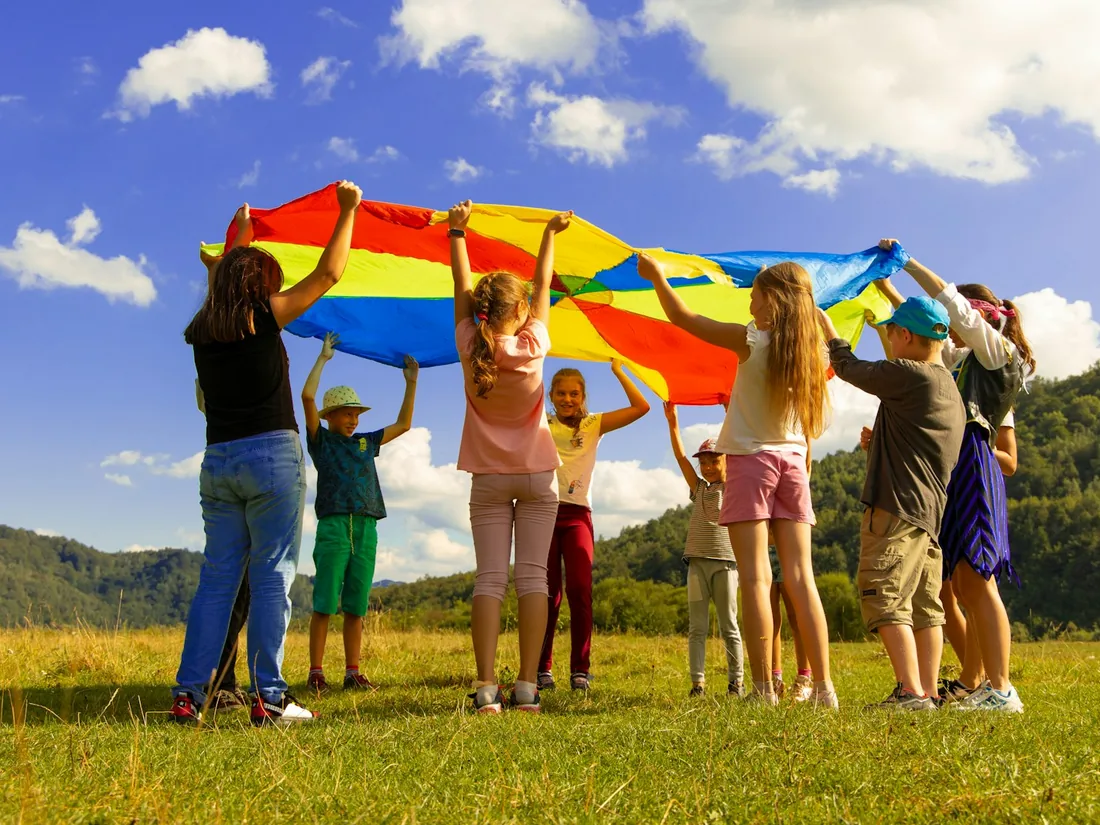 Children playing with a colorful parachute at summer camp