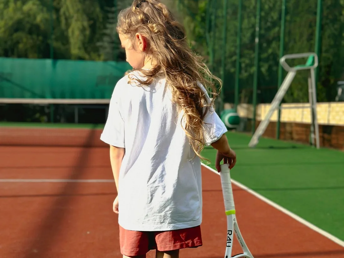 Young player holding a racket on a clay tennis court
